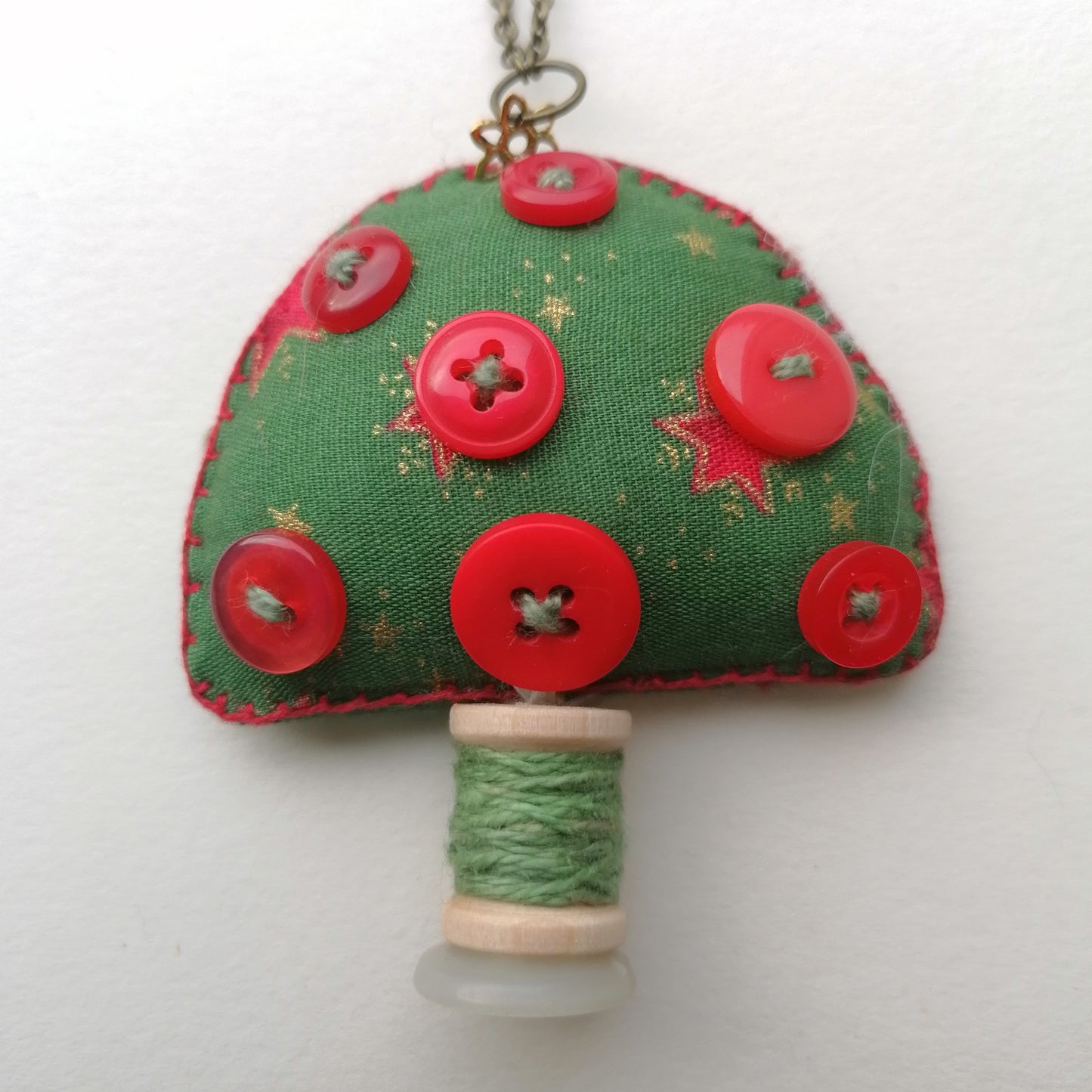 Green Fabric toadstool ornament with red buttons and wooden spool.
