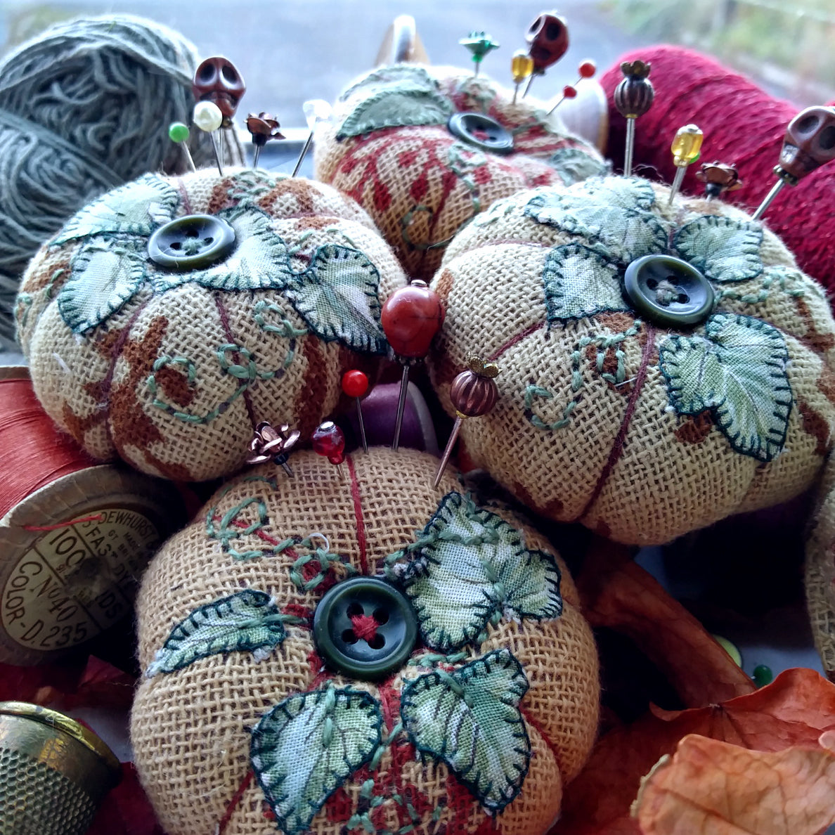Pumpkin pincushions with spools and autumn leaves