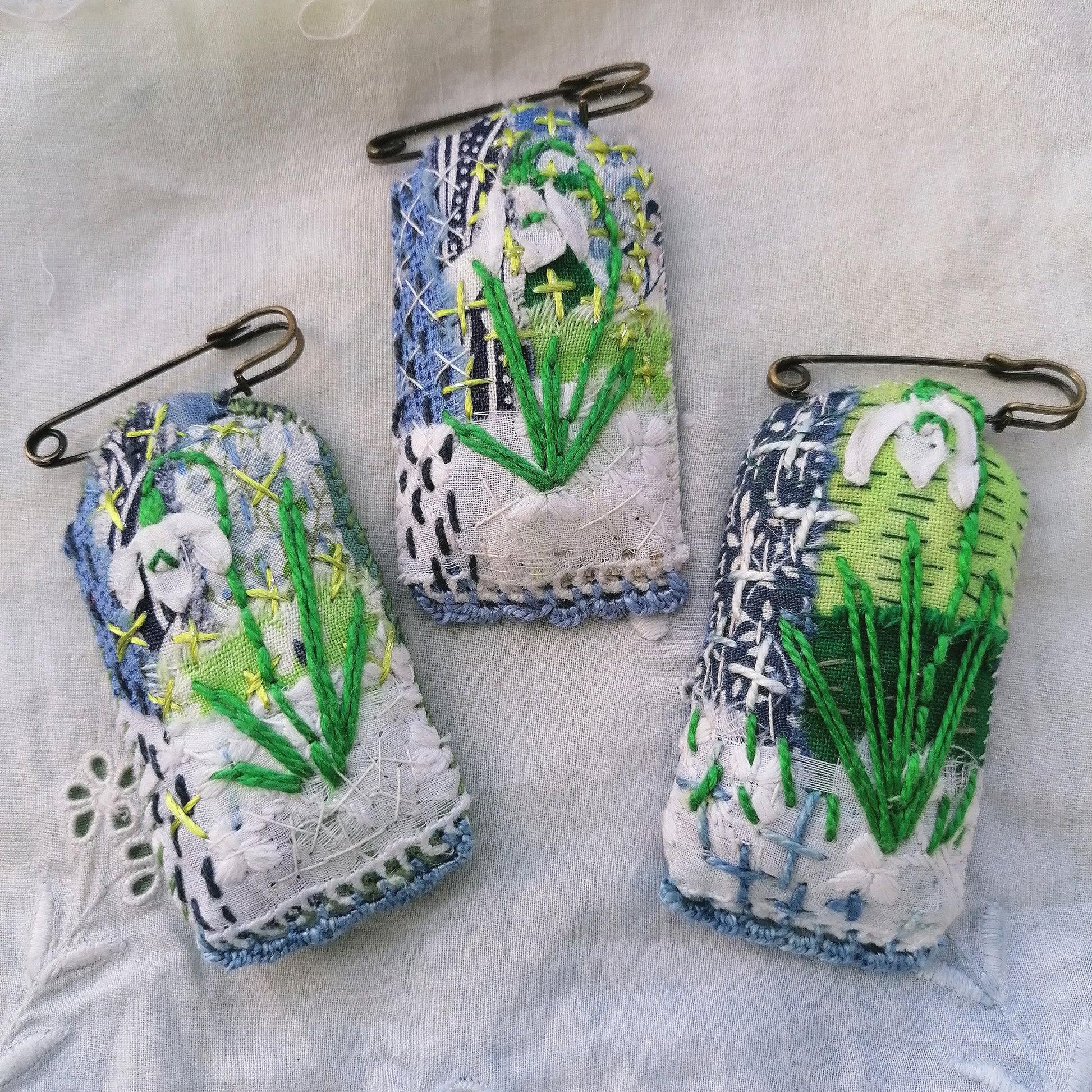 Tag shaped, padded and embroidered snowdrop brooches on vintage style bronze tone kilt pins