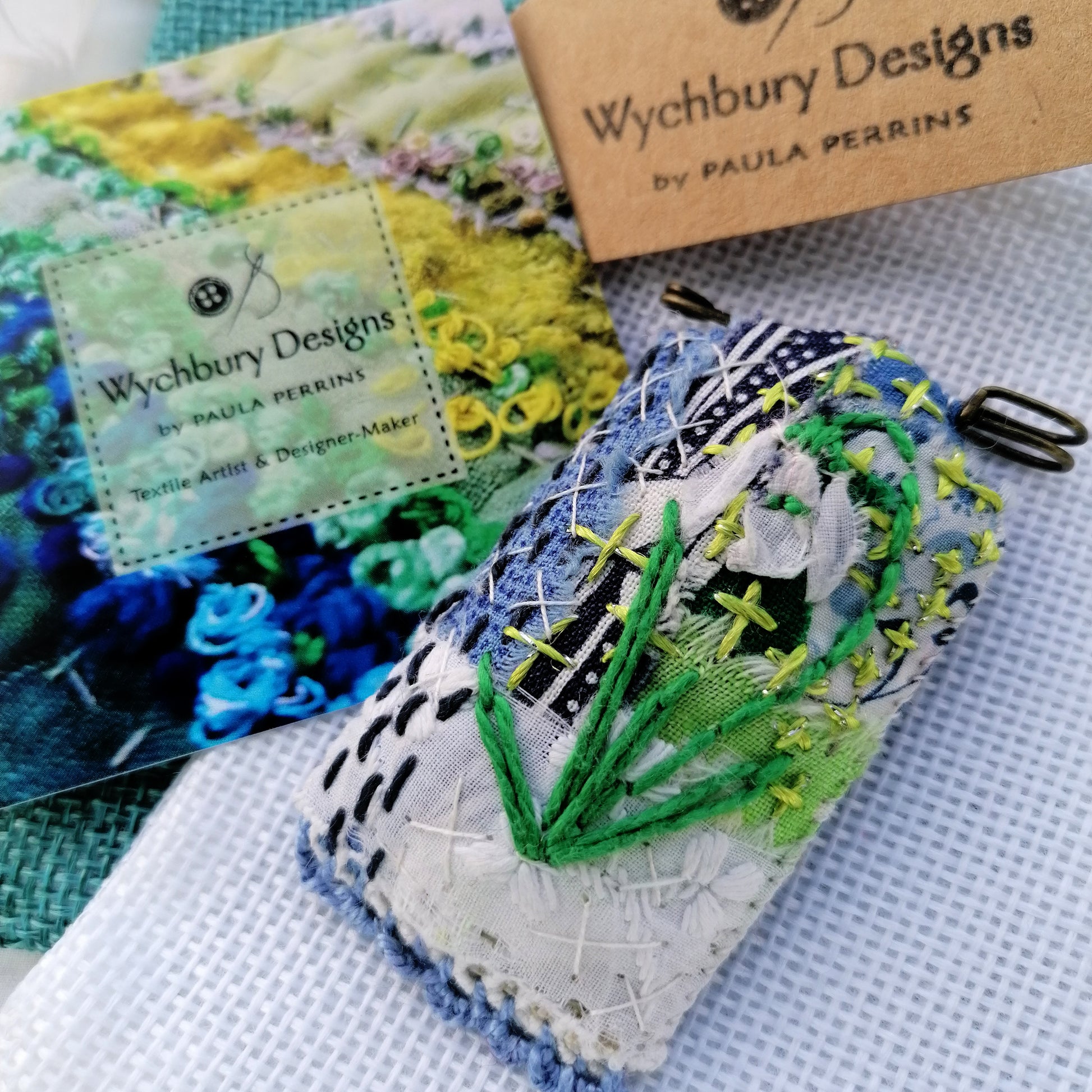Tag shaped, padded and embroidered snowdrop brooch 2 on vintage style bronze tone kilt pin. pictured with gift bag and business card.