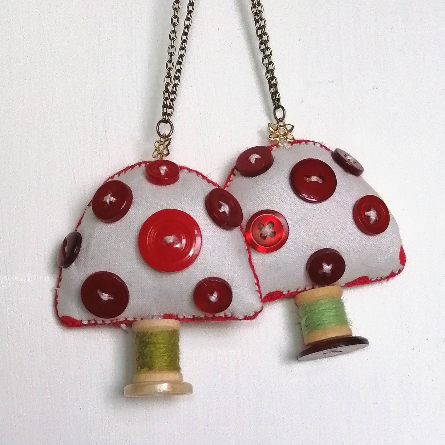 White Fabric toadstool ornament with red buttons and wooden spool.